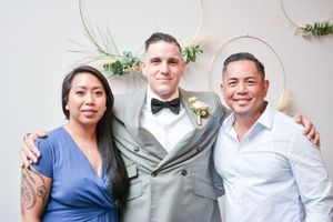 Wedding party members in formal attire pose together against a white backdrop.