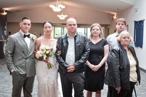 A formal wedding party group photo taken indoors with a chandelier in the background.