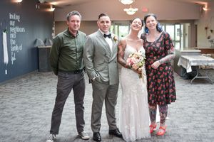 Wedding party poses together in casual attire on carpeted floor.
