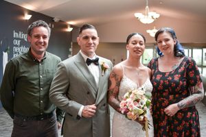 Wedding celebration with guests and couple gathered in indoor reception space.
