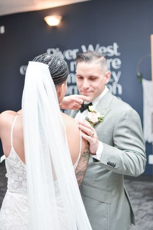 Wedding couple sharing tender moment against dark wall with signage.