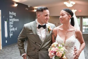 Newlyweds share candid moments together in an indoor reception venue with decorative wall text.