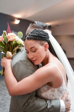 Tender embrace between newlyweds with soft lighting and floral details.