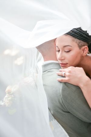Ethereal bridal portrait with soft white veil and gentle embrace.