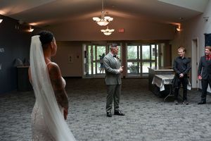 A wedding ceremony takes place in an elegant indoor venue with chandelier lighting and carpeted floors.