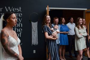 Wedding guests gathered against a dark wall during reception celebrations.