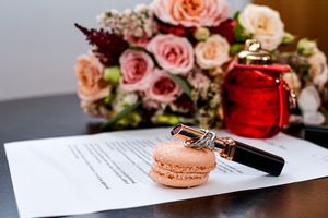 Wedding details featuring pink roses, rings, and documents with romantic styling.