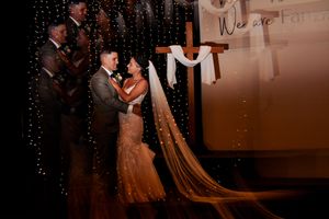 Romantic first dance sequence at a wedding reception with twinkling lights in the background.