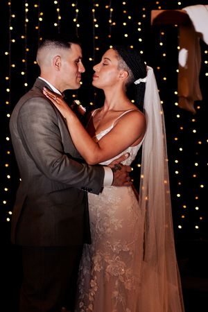 Romantic wedding couple shares intimate moment against twinkling fairy light backdrop.