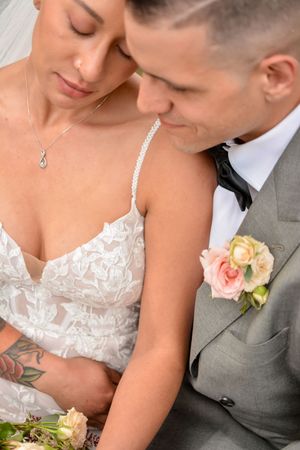 Romantic wedding couple in grey suit and white lace dress share intimate moments during their photoshoot.