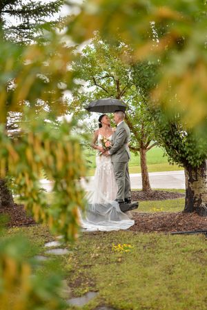 Romantic wedding couple embracing under autumn trees in a park setting.