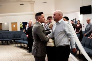 Wedding guests gathered in a reception hall sharing warm embraces and congratulations.