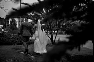 Artistic black and white silhouette of wedding couple outdoors among trees.
