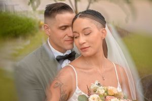 Tender moment between newlyweds with floral bouquet in outdoor setting.