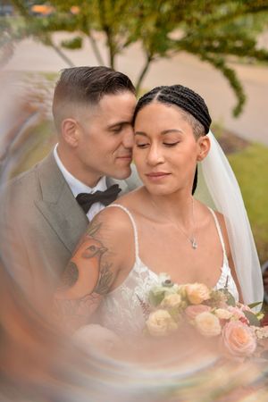 Romantic wedding portrait with soft natural lighting and garden foliage in background.