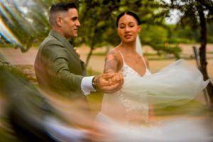 A romantic wedding couple dancing together outdoors in soft natural lighting.