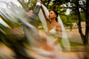 A joyful moment captured through creative lens flare as a bride dances outdoors.