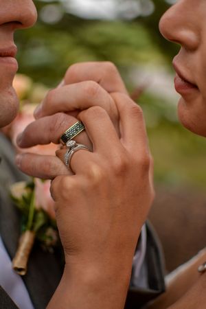 Close-up of hands showing off elegant wedding rings with engagement ring details.