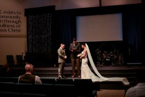 A couple in formal wedding attire dances together during their first dance at a dimly lit reception venue.