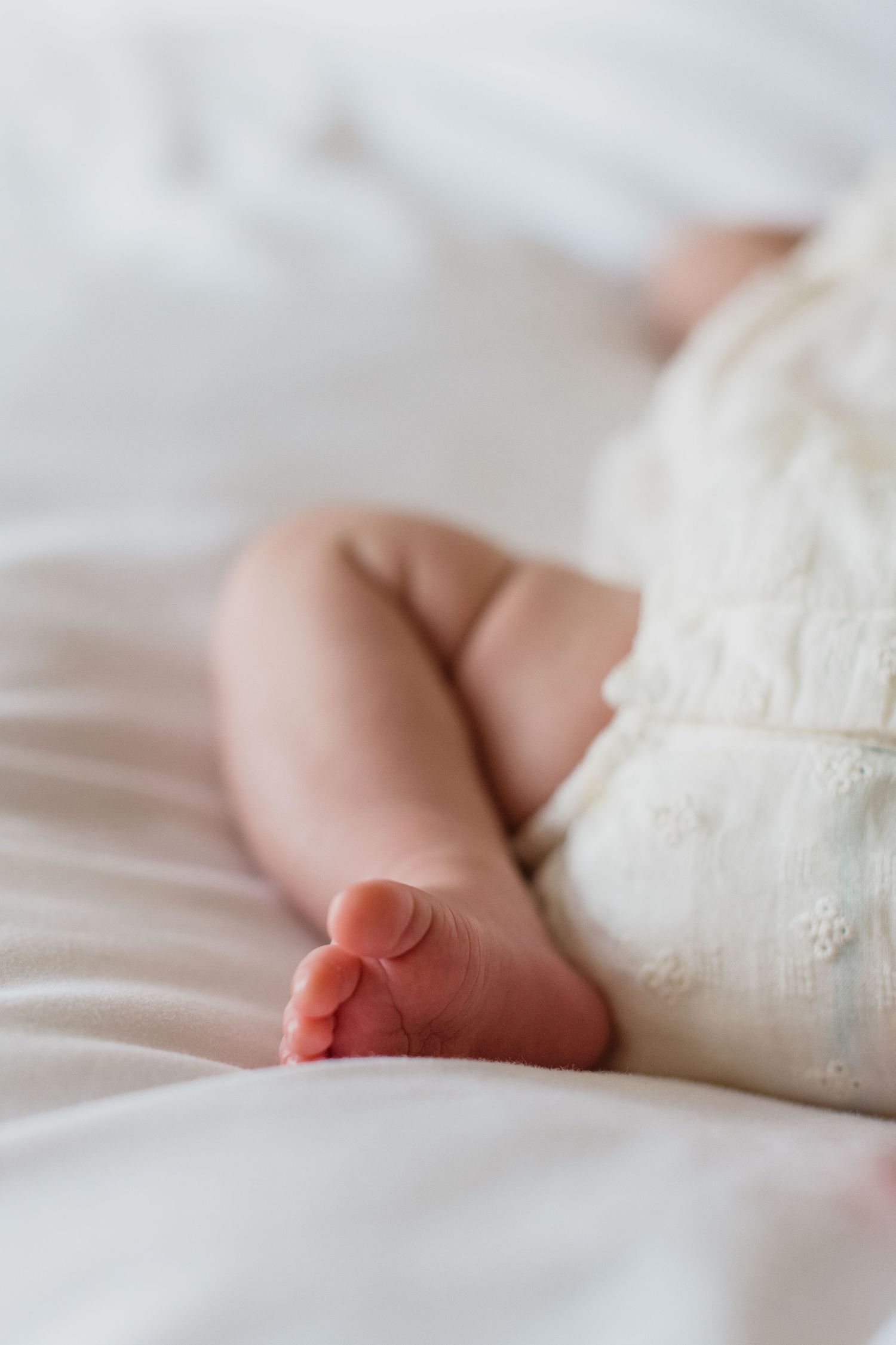 A series of tender moments between a mother in a white dress and her newborn baby against a neutral background.