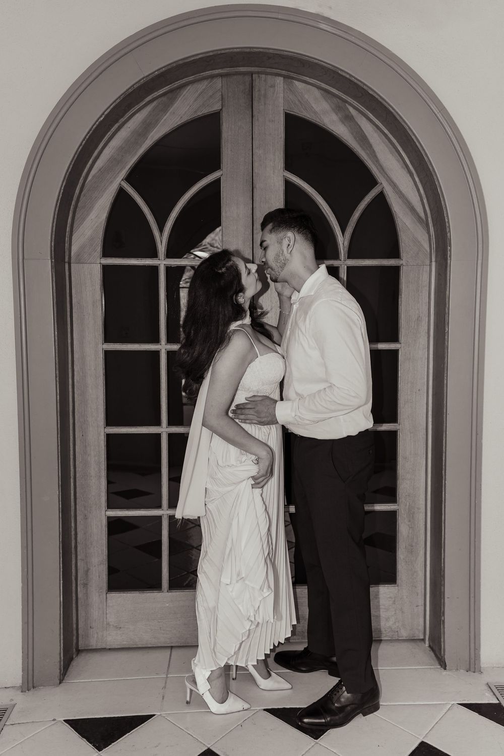 A romantic sequence of black and white photos showing couples in evening attire sharing intimate moments in an arched hallway.