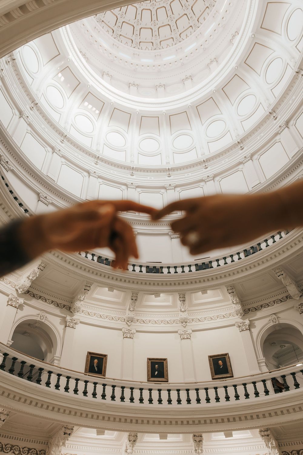 Ornate white dome interior of a government building with decorative architectural details and circular patterns.