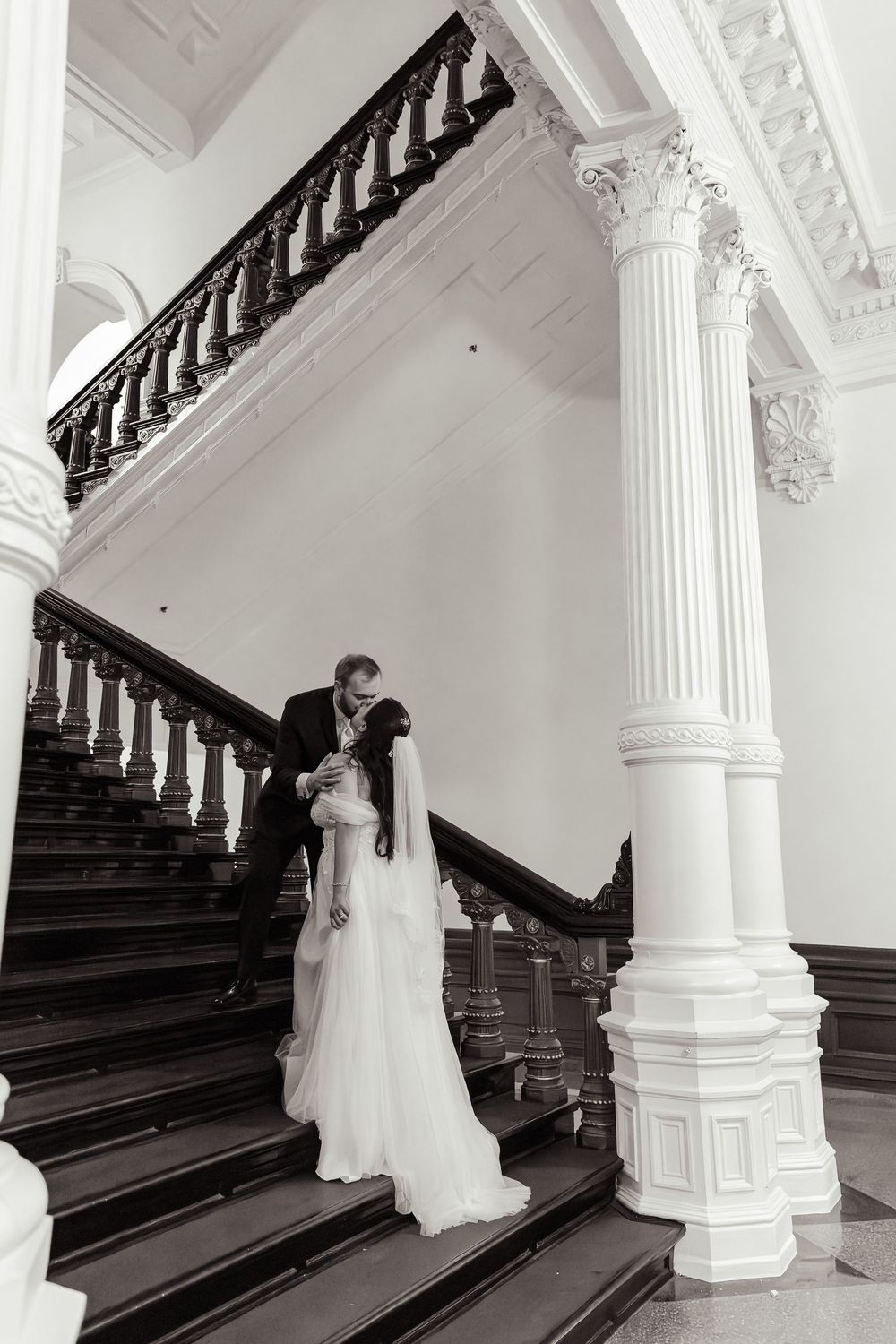 A series of elegant black and white wedding photos showing a couple on a grand staircase with white columns.