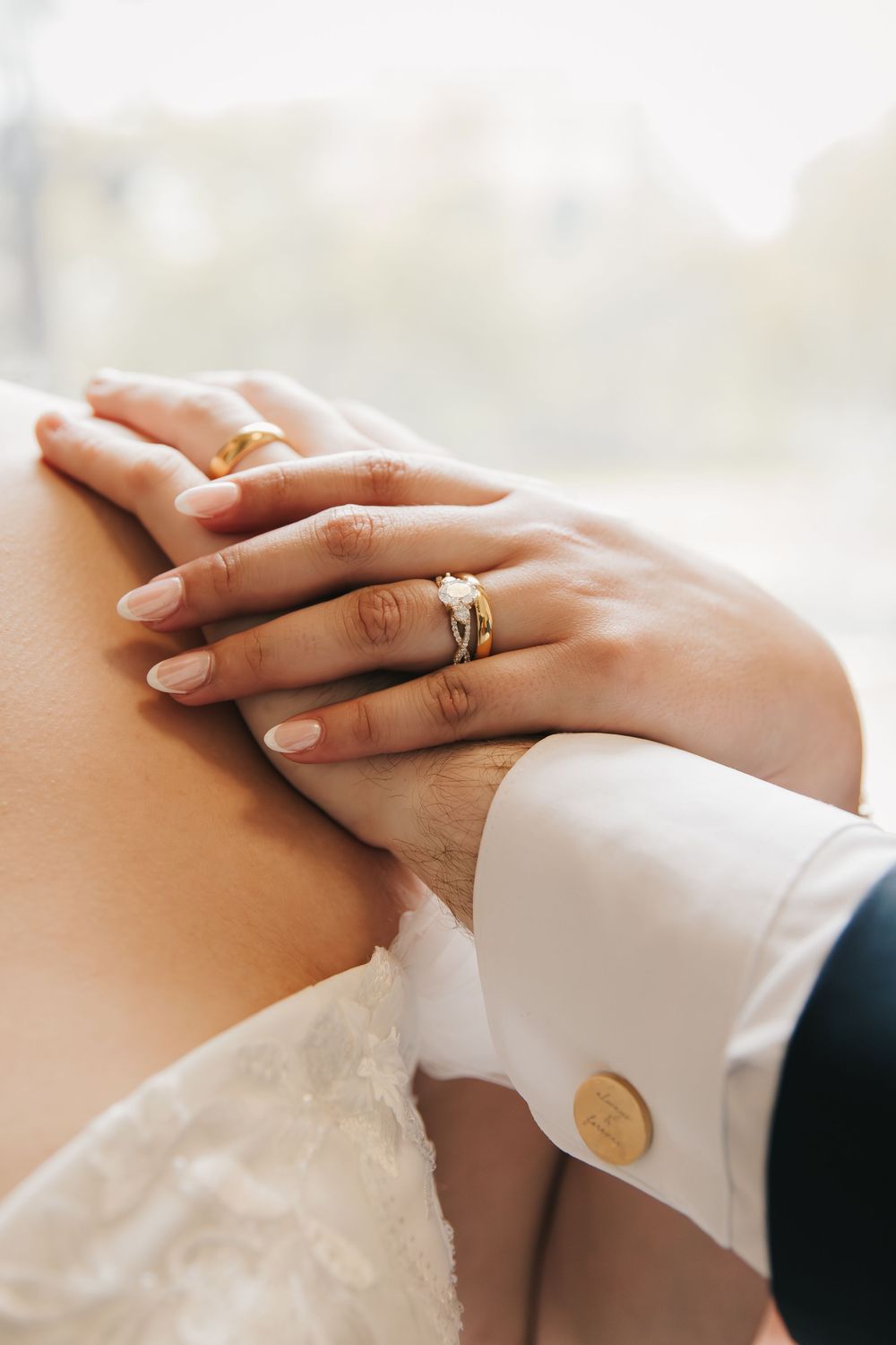 Close-up sequence of hands exchanging wedding rings during marriage ceremony, showing white sleeves and delicate fingers.