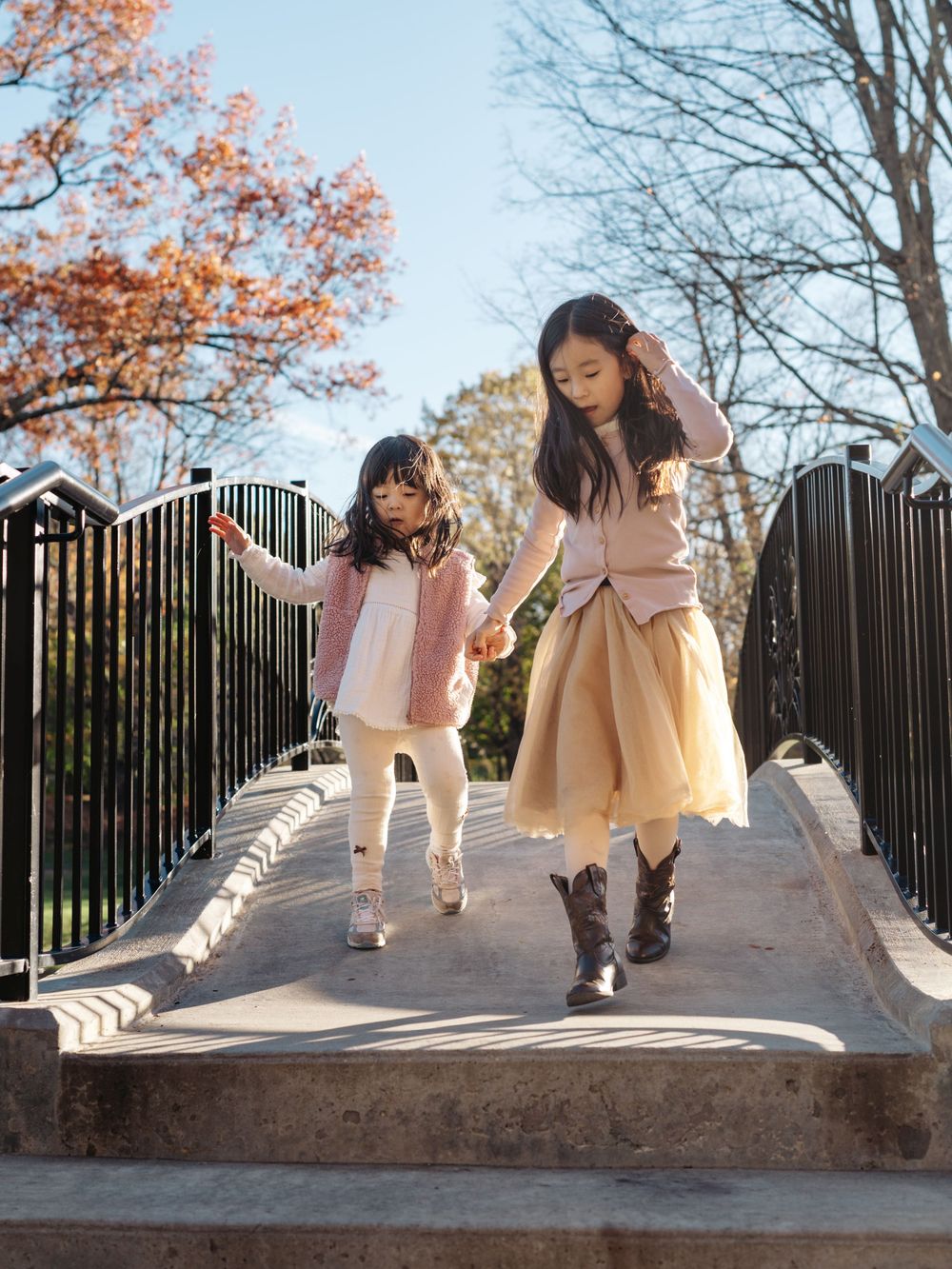 People playing and interacting on a concrete bridge with fall foliage visible in the background.