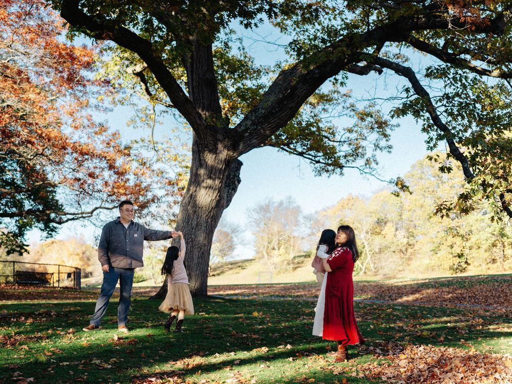A couple dances together in the Larz Anderson Park in Brookline, MA surrounded by autumn leaves and trees during a golden sunset.