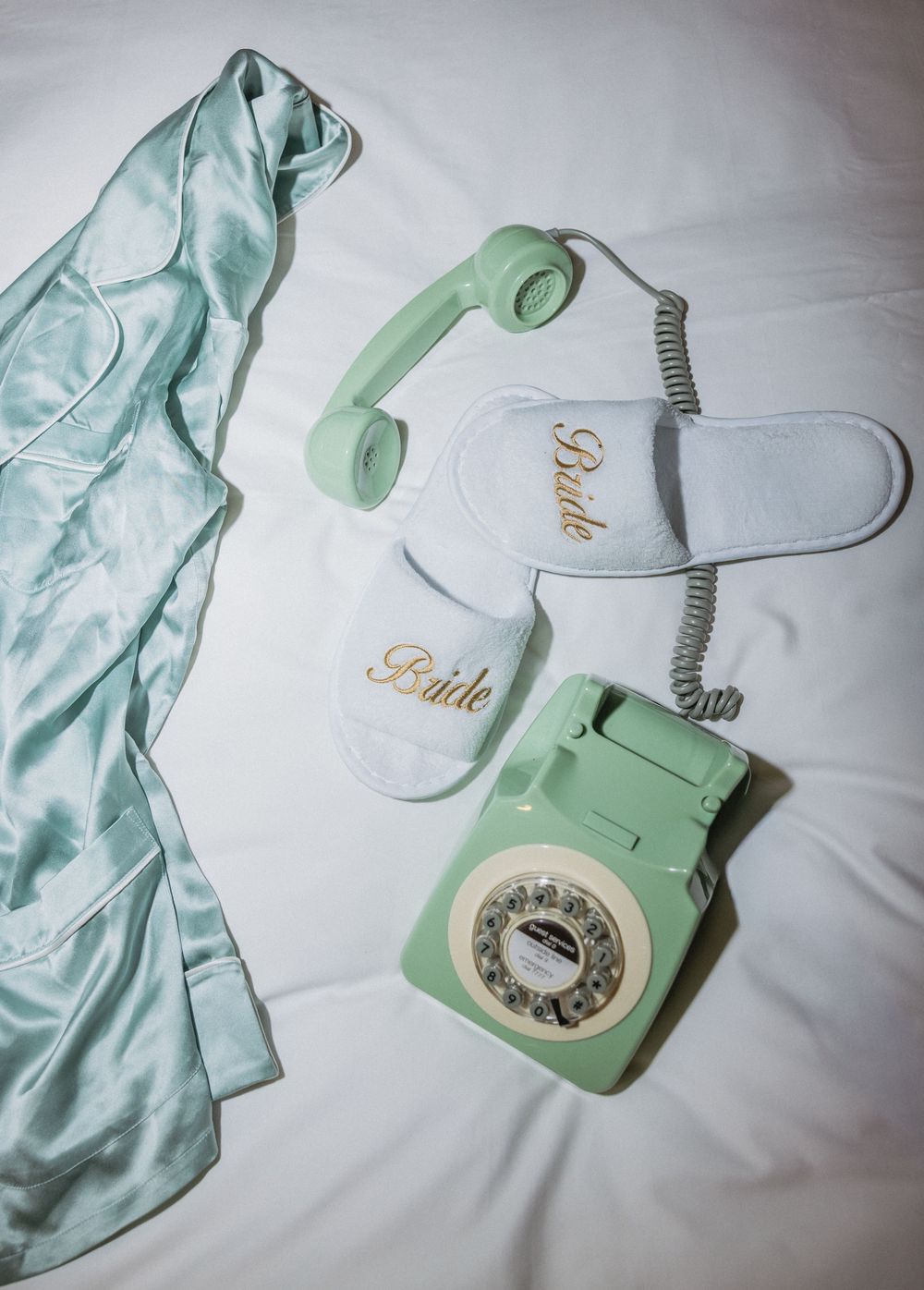 Vintage mint green rotary telephone with silk fabric on white background.