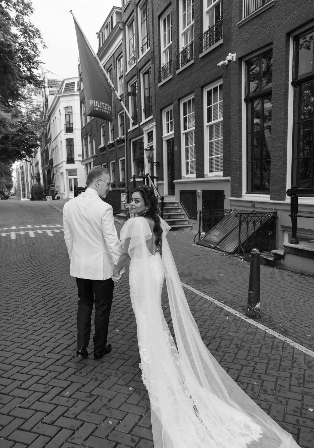 Newlyweds walking along a historic brick street with traditional architecture.