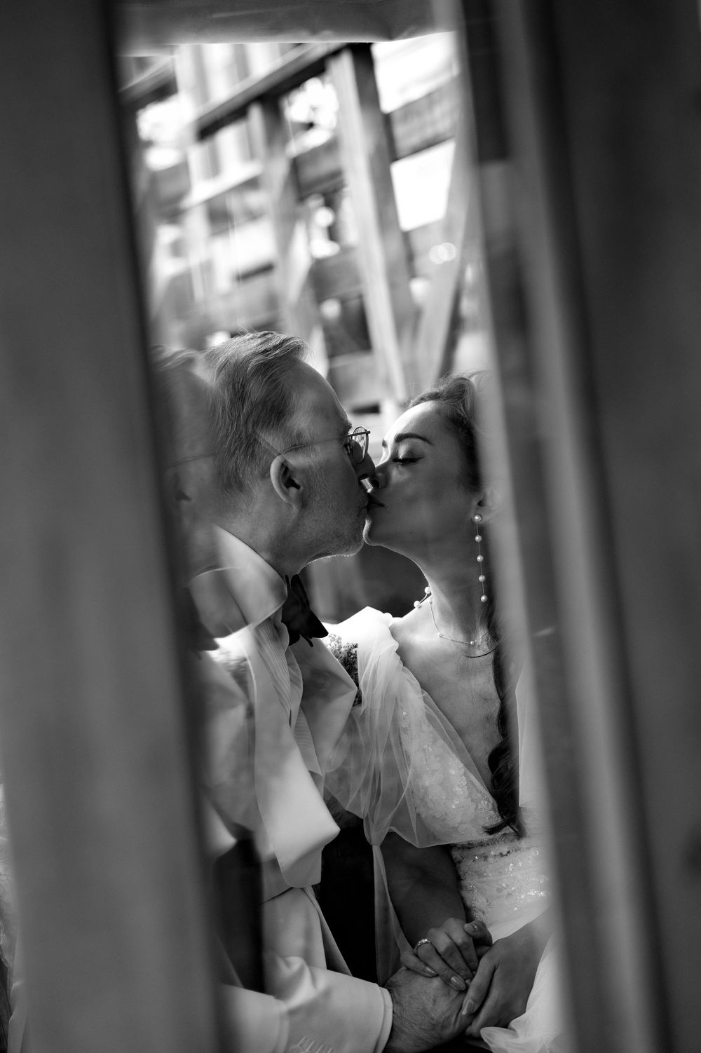 Artistic black and white wedding portraits through window reflections.
