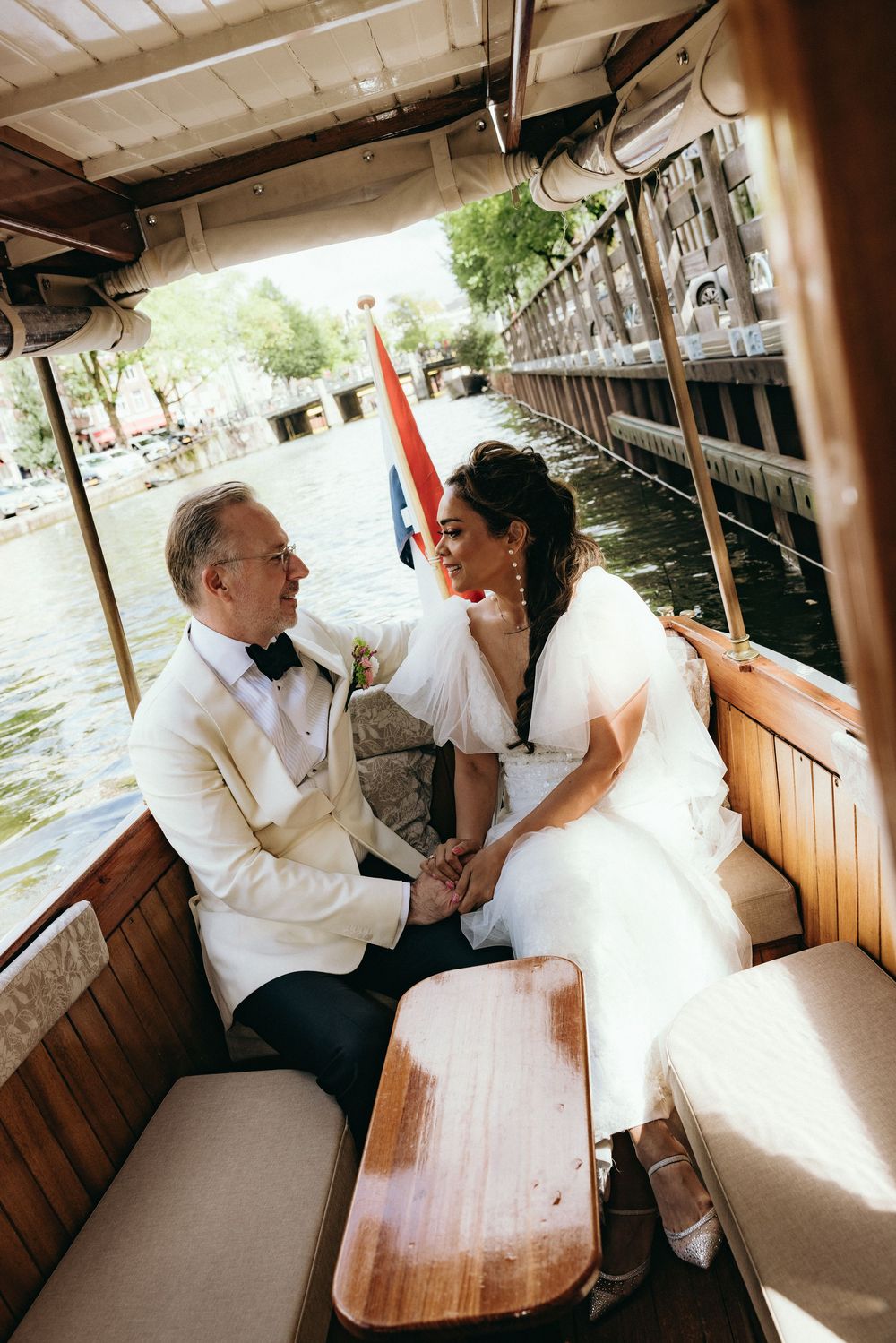 Wedding couple sharing romantic moments aboard a wooden boat on the water.