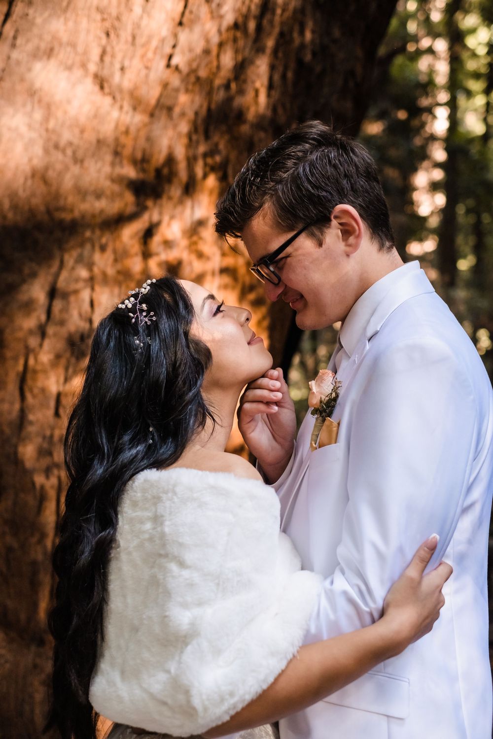 A romantic couple shares intimate moments against a backdrop of towering redwood trees in a forest setting. Santa Cruz California