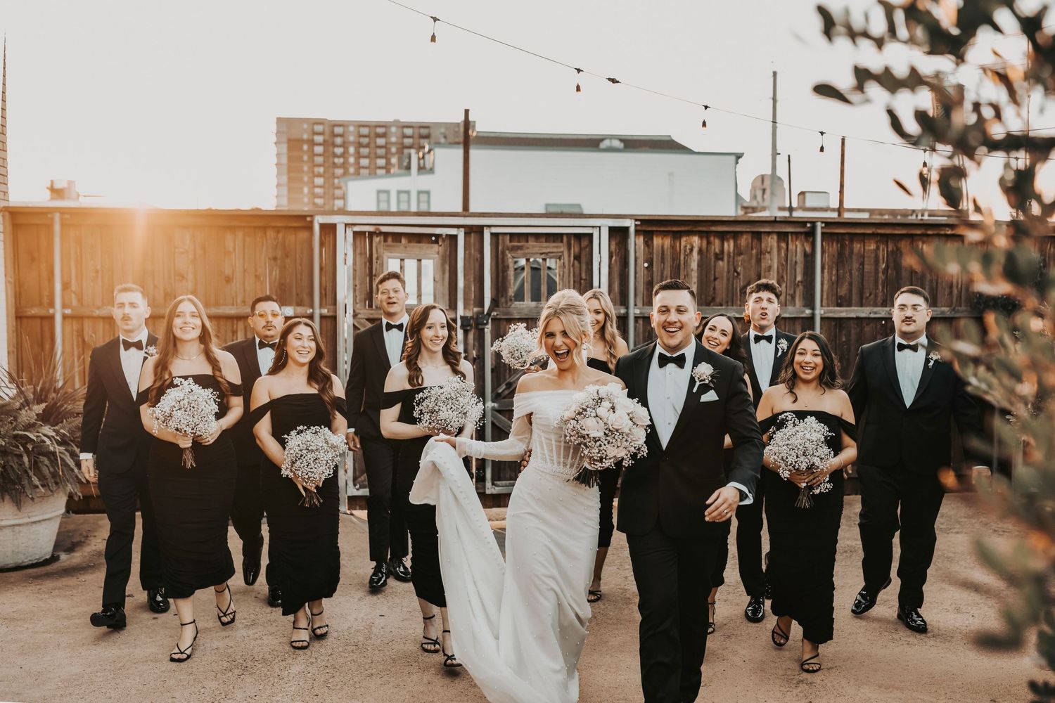 Modern editorial wedding party portraits at sunset, friends cheering and walking together outside Brake & Clutch Warehouse.