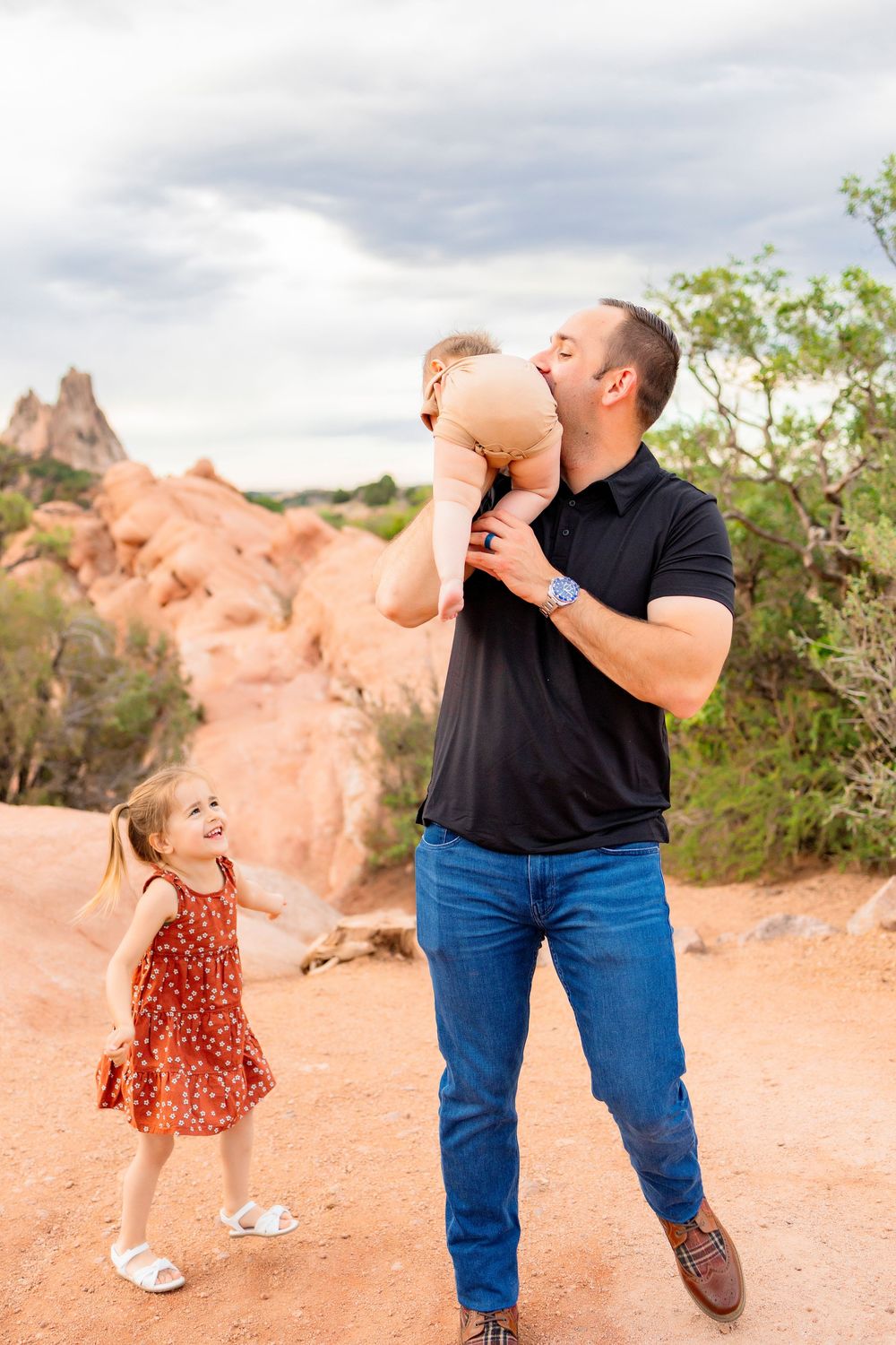 A dad playing with his two children at the garden of the gods