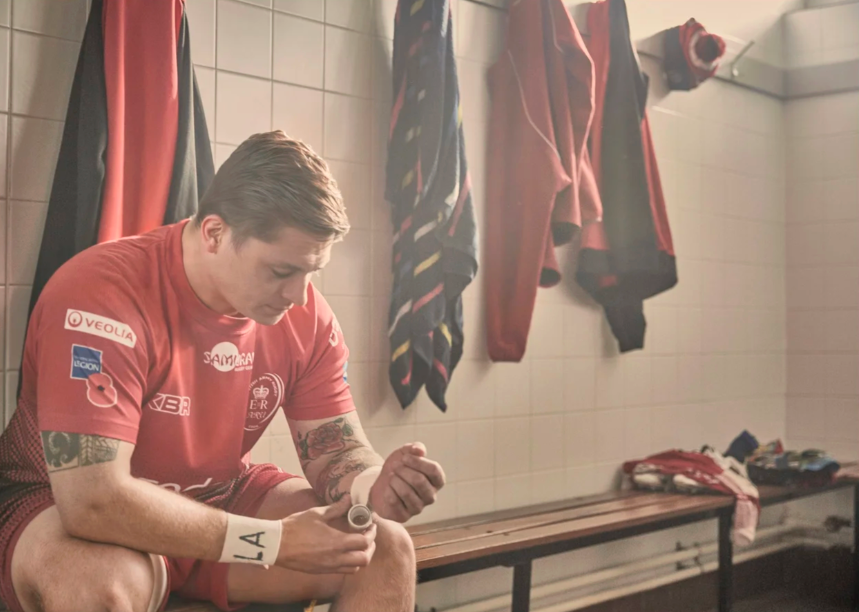 Players in red jerseys preparing in locker room before match.