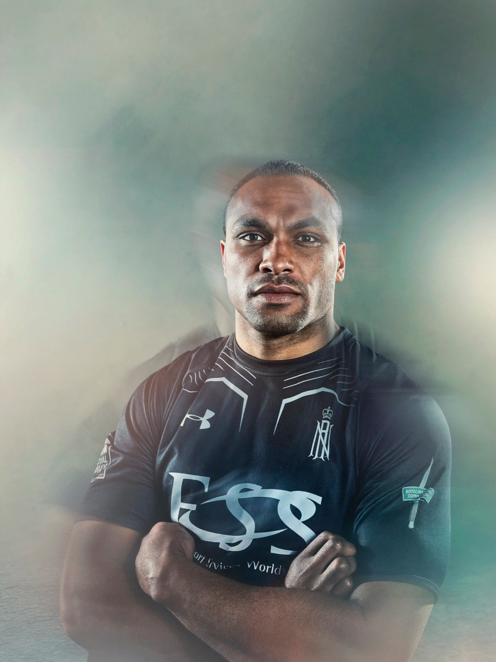 Athlete wearing black Under Armour jersey poses against moody background.