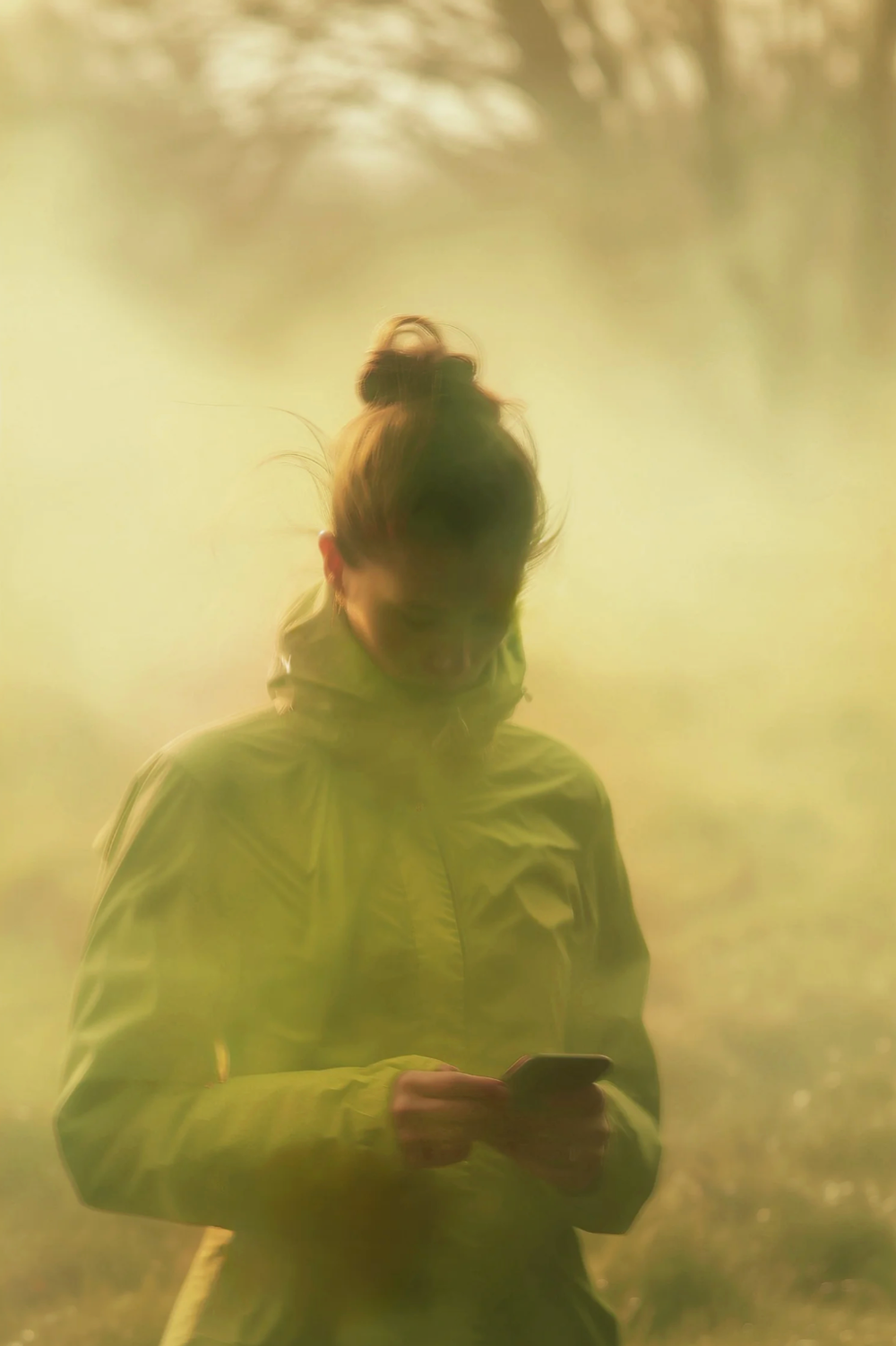 Figure in yellow hoodie captured in dreamy motion blur against misty background.