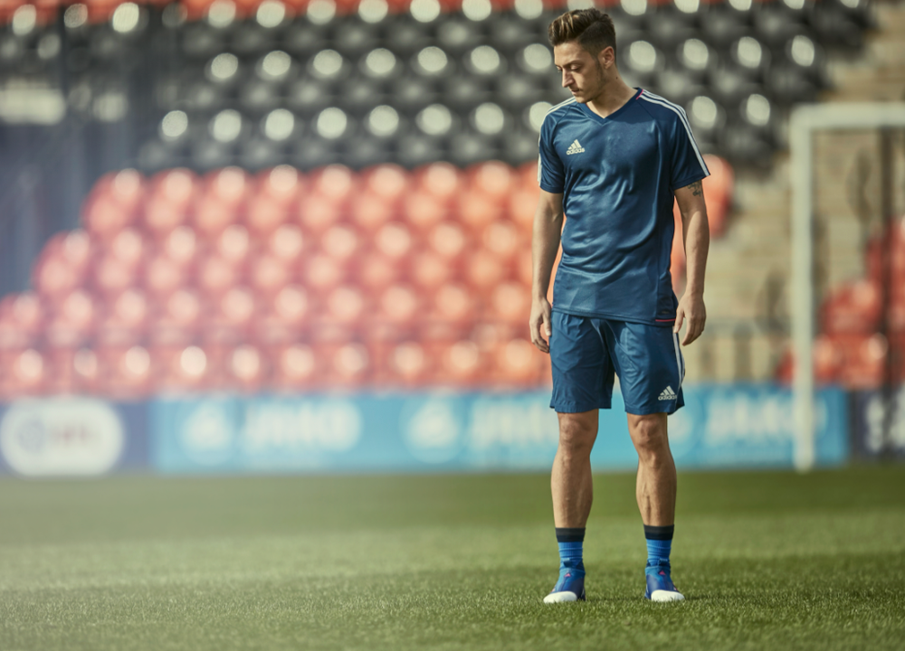 Soccer player in blue Adidas uniform practicing on field during training session.