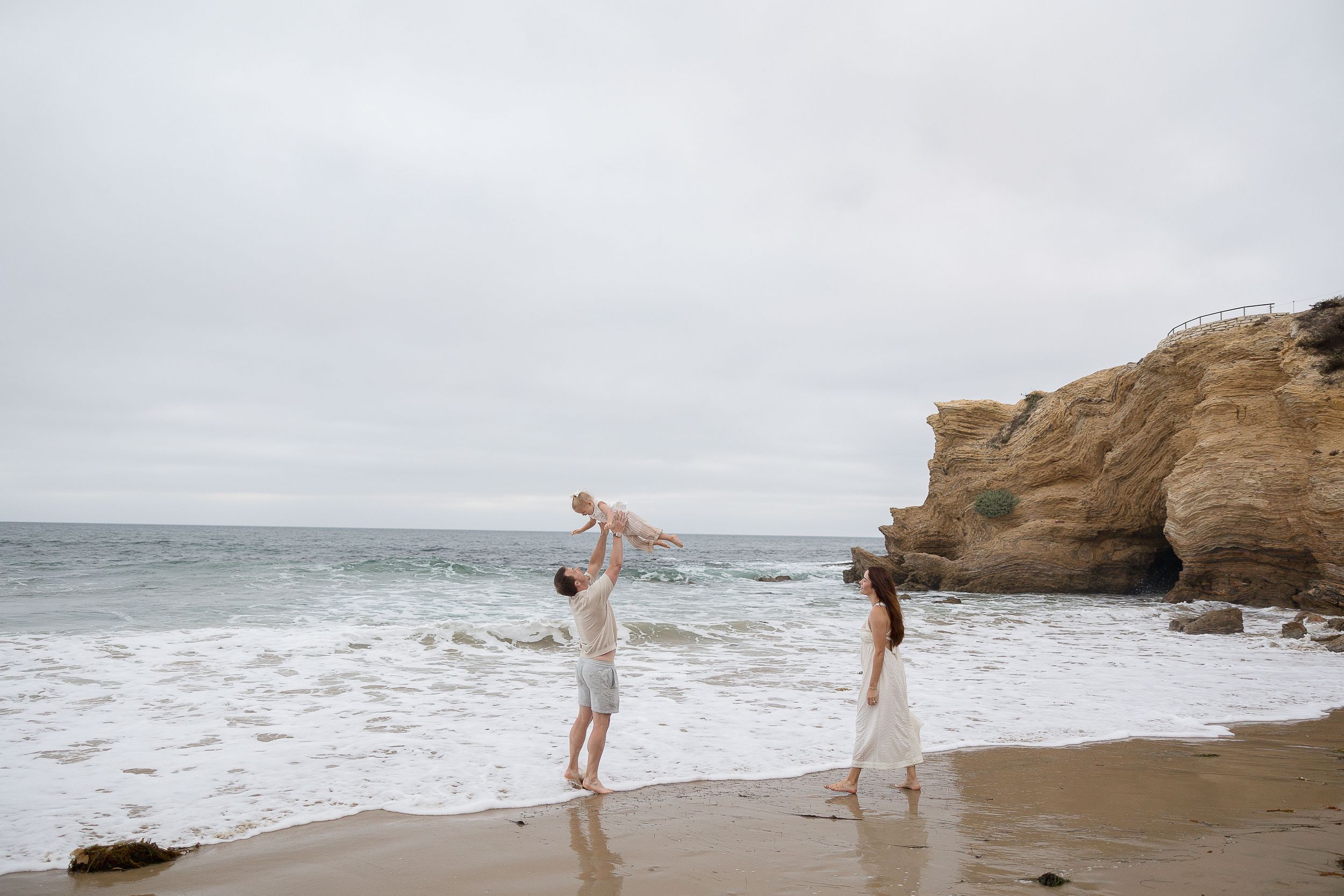 Crystal Cove beach session with dad lifting toddler in the air