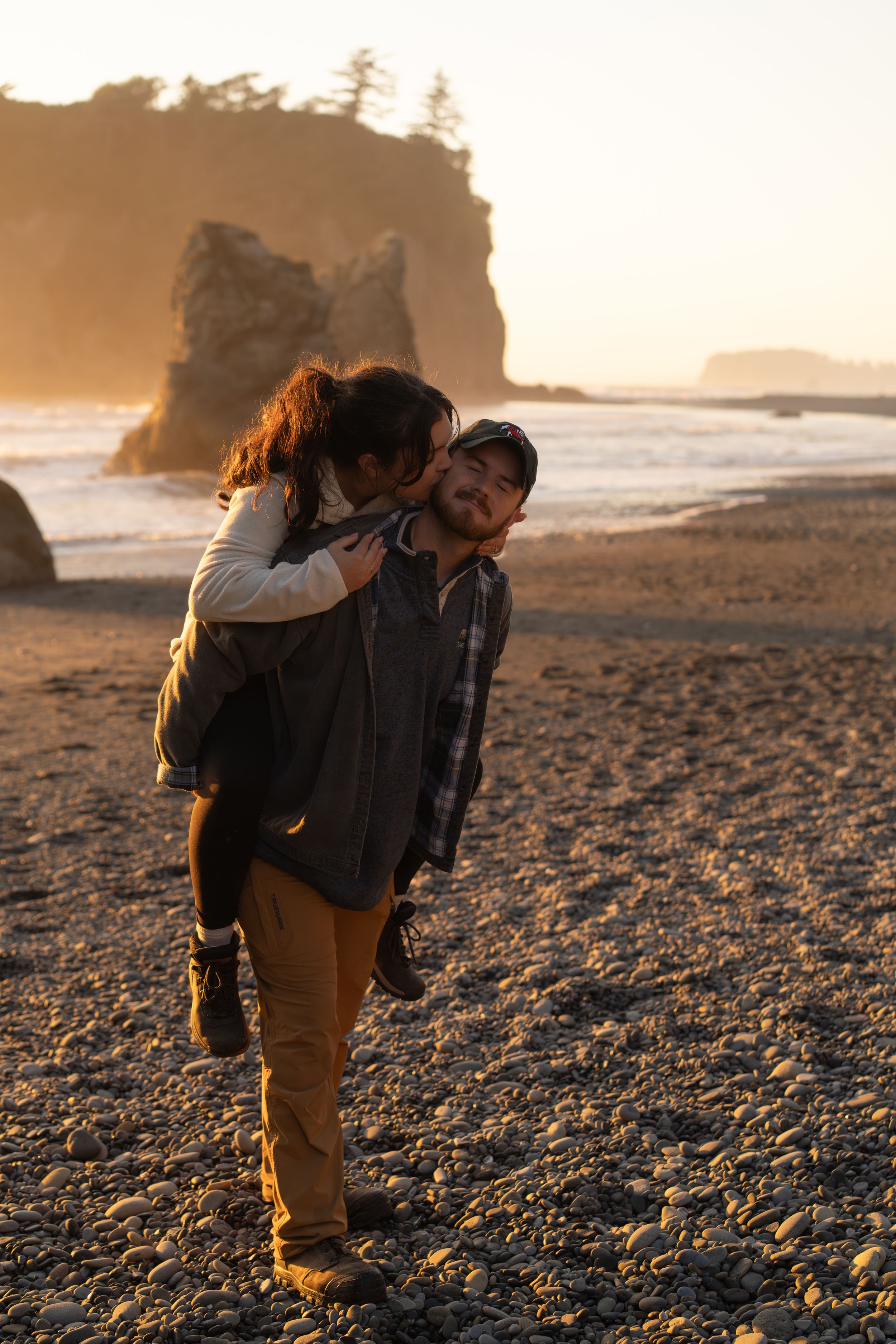A couple at Ruby beach at sunset with dramatic coastal cliffs and golden light in the background captured by Savvy Photography - PNW