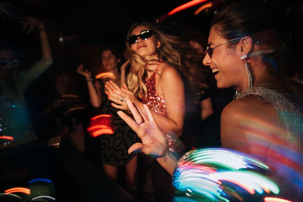 Colorful light trails and motion blur create an abstract pattern at a dark nightclub or party scene.