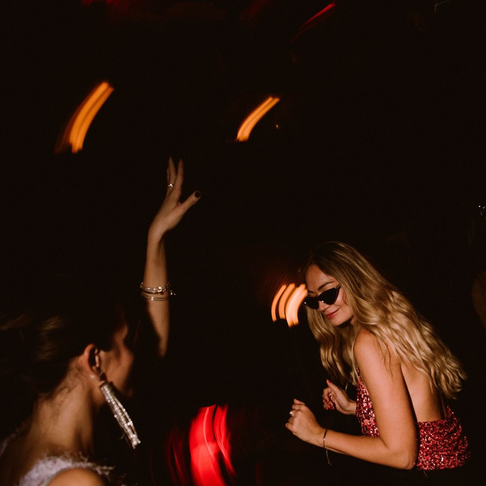 Energetic nightclub scene with dancers moving under dramatic red and orange lighting.