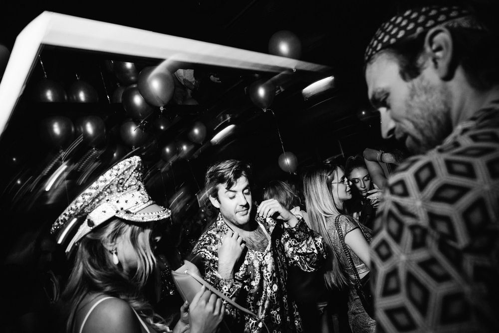 Black and white photo of an energetic crowd at a concert with dramatic lighting effects.