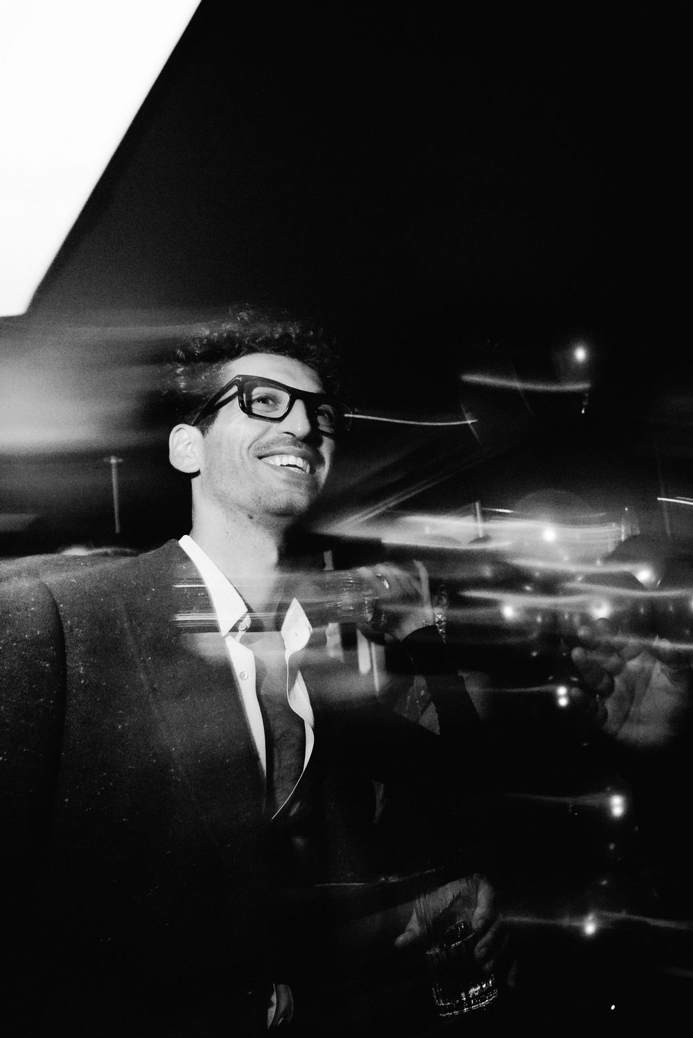 Black and white nighttime scene showing silhouettes against bright lights and reflections.