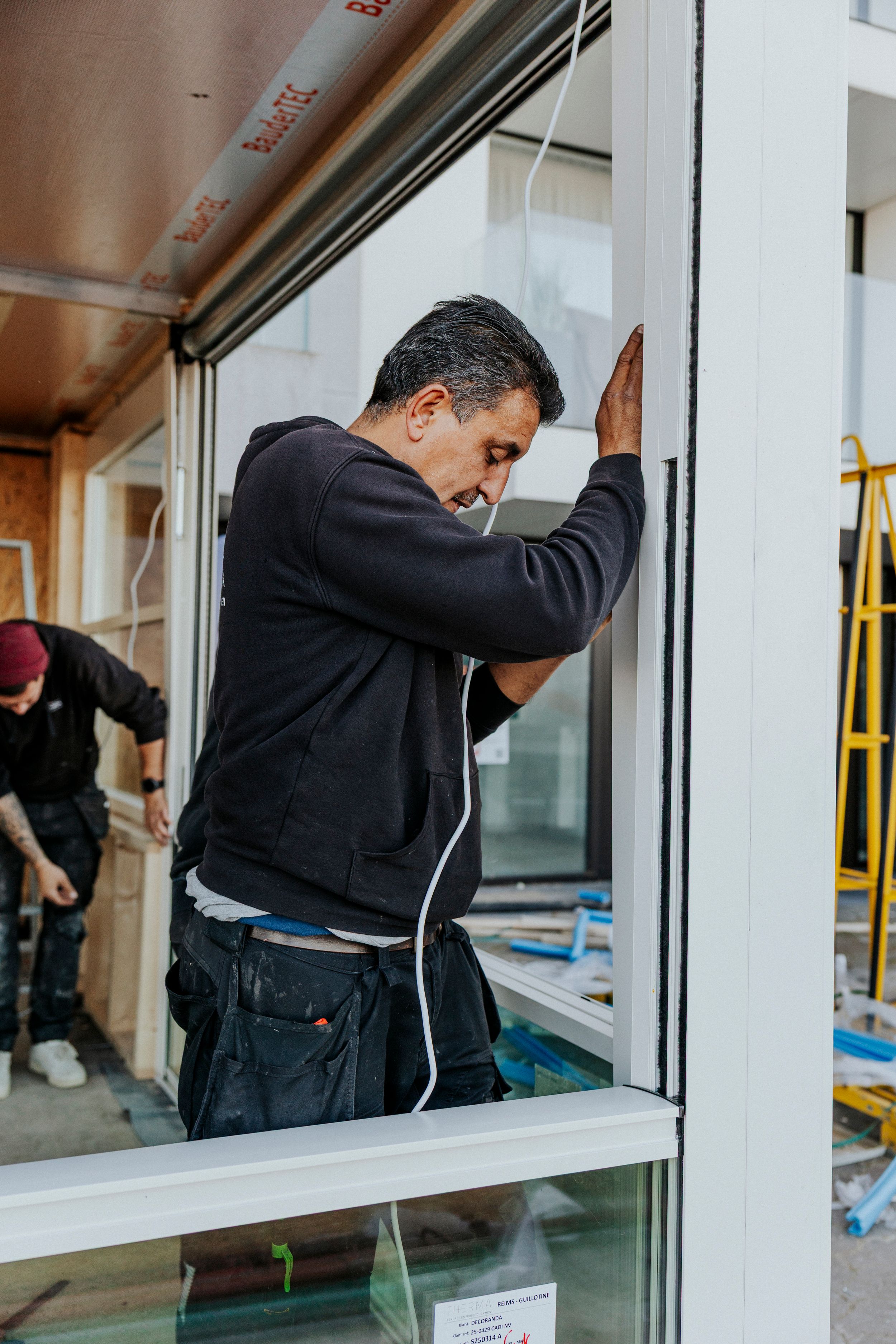 Construction worker installing large glass window panels in commercial building.