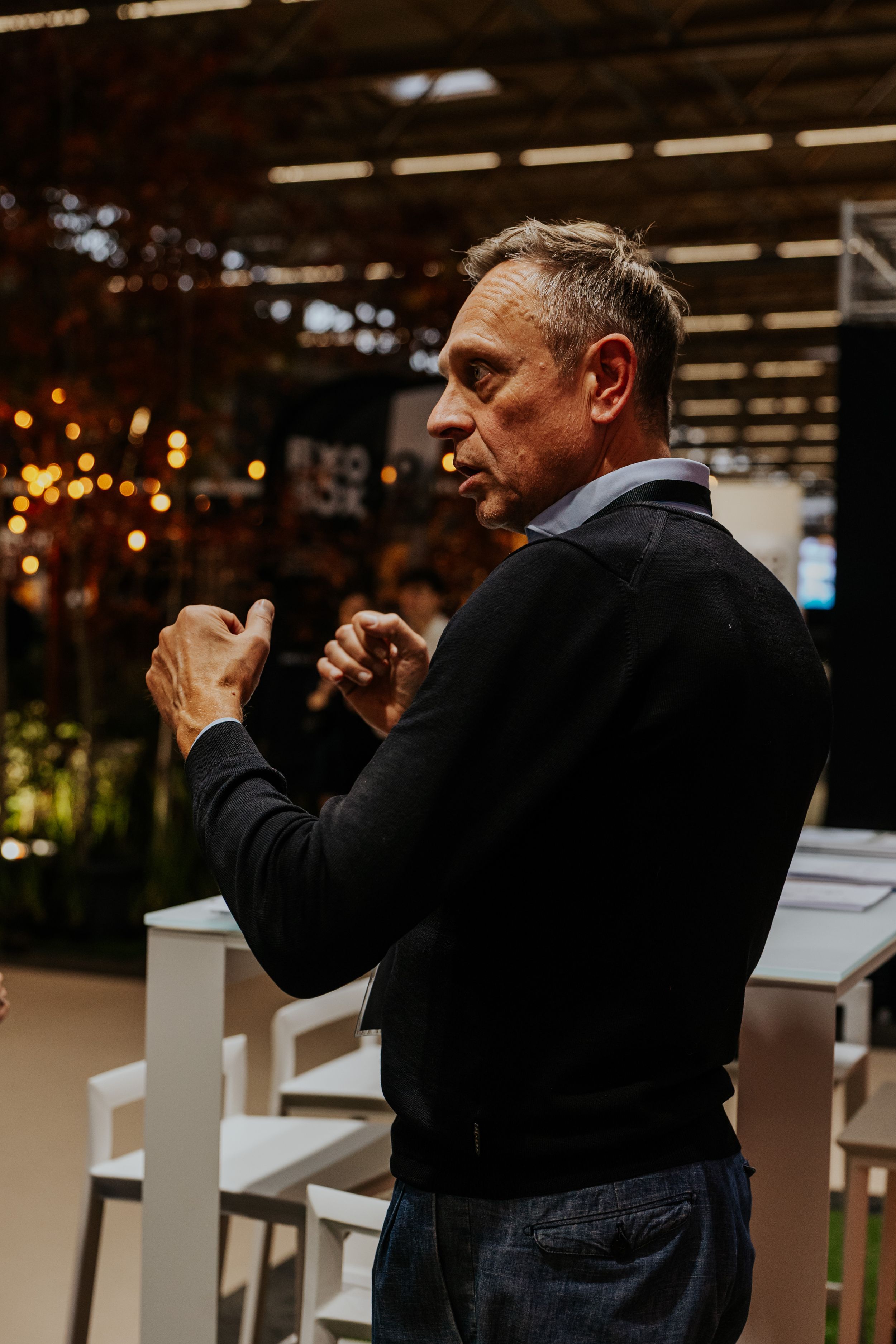 Person in black suit taking photos with a professional camera in a dimly lit indoor setting.