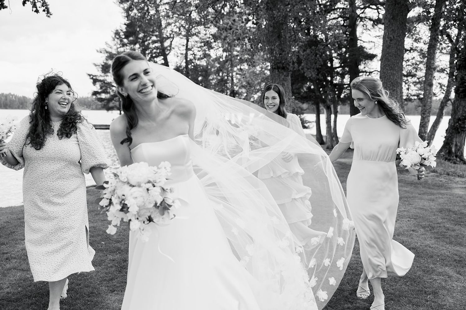 A group of people in white outfits dance joyfully outdoors in a park setting.